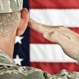 Servicemember saluting a flag